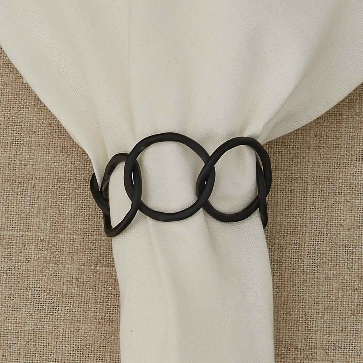 close up of chainlink metal napkin ring white napkin beige wonven surface