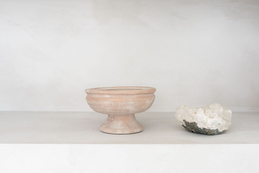 single rustic pedestal vase with geological knick knack to the right of the vase