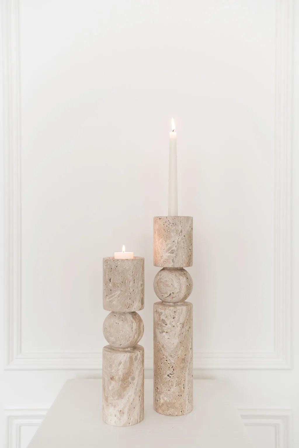 two travertine stone candle holders one with a tealight and the other with a taper candle