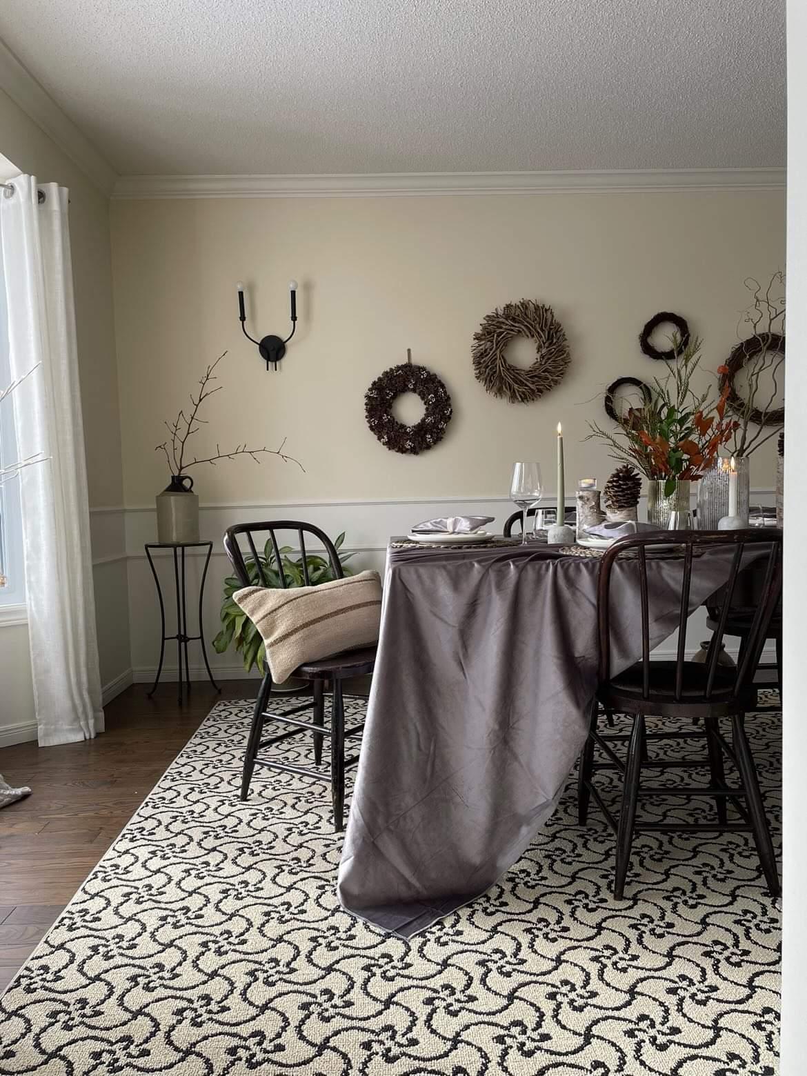 dinning room with patterned rug and table with slate velvet table cloth draped table is fully set