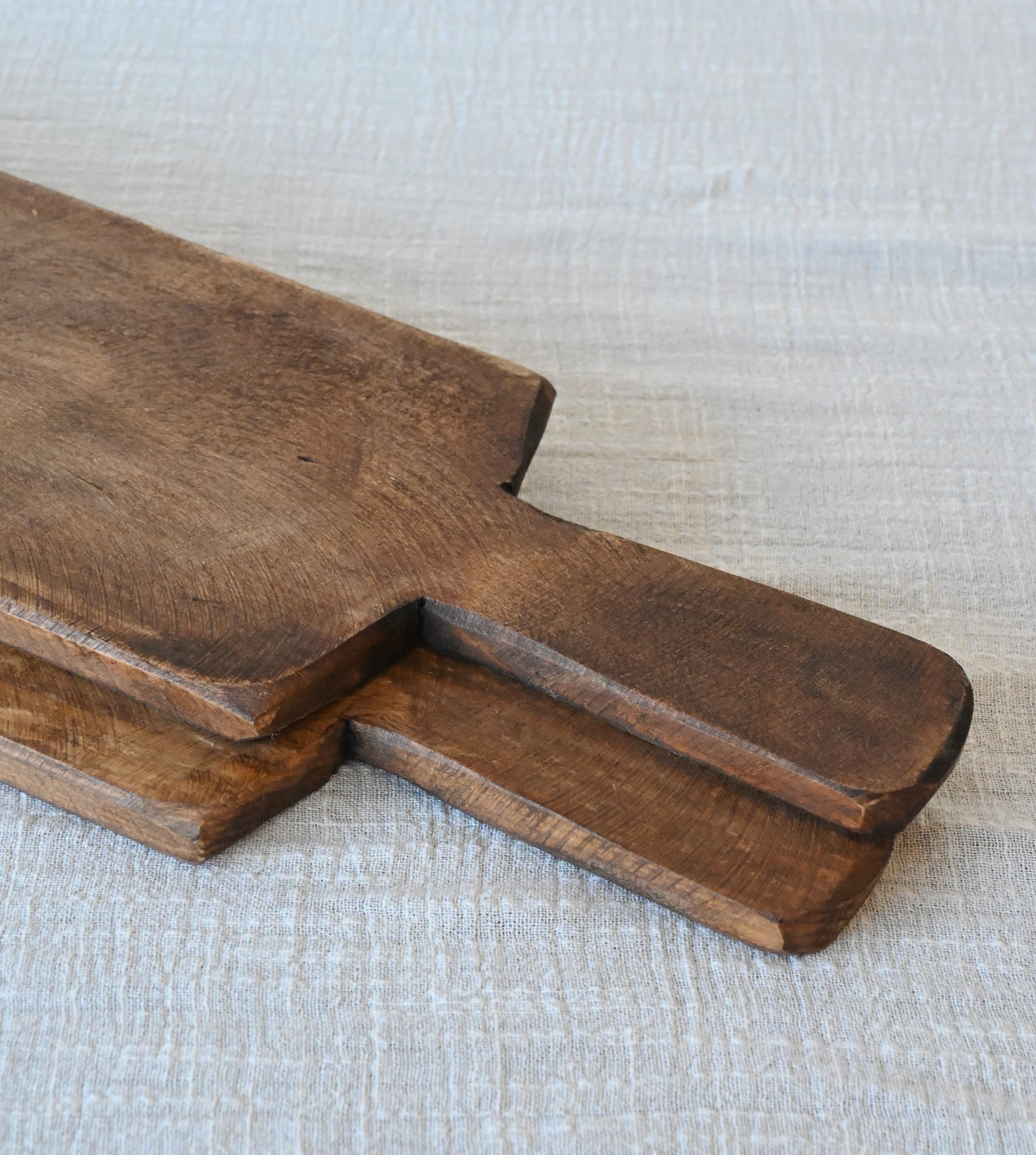 two mango wood charcuterie boards sitting on top of oatmeal gauze table runner