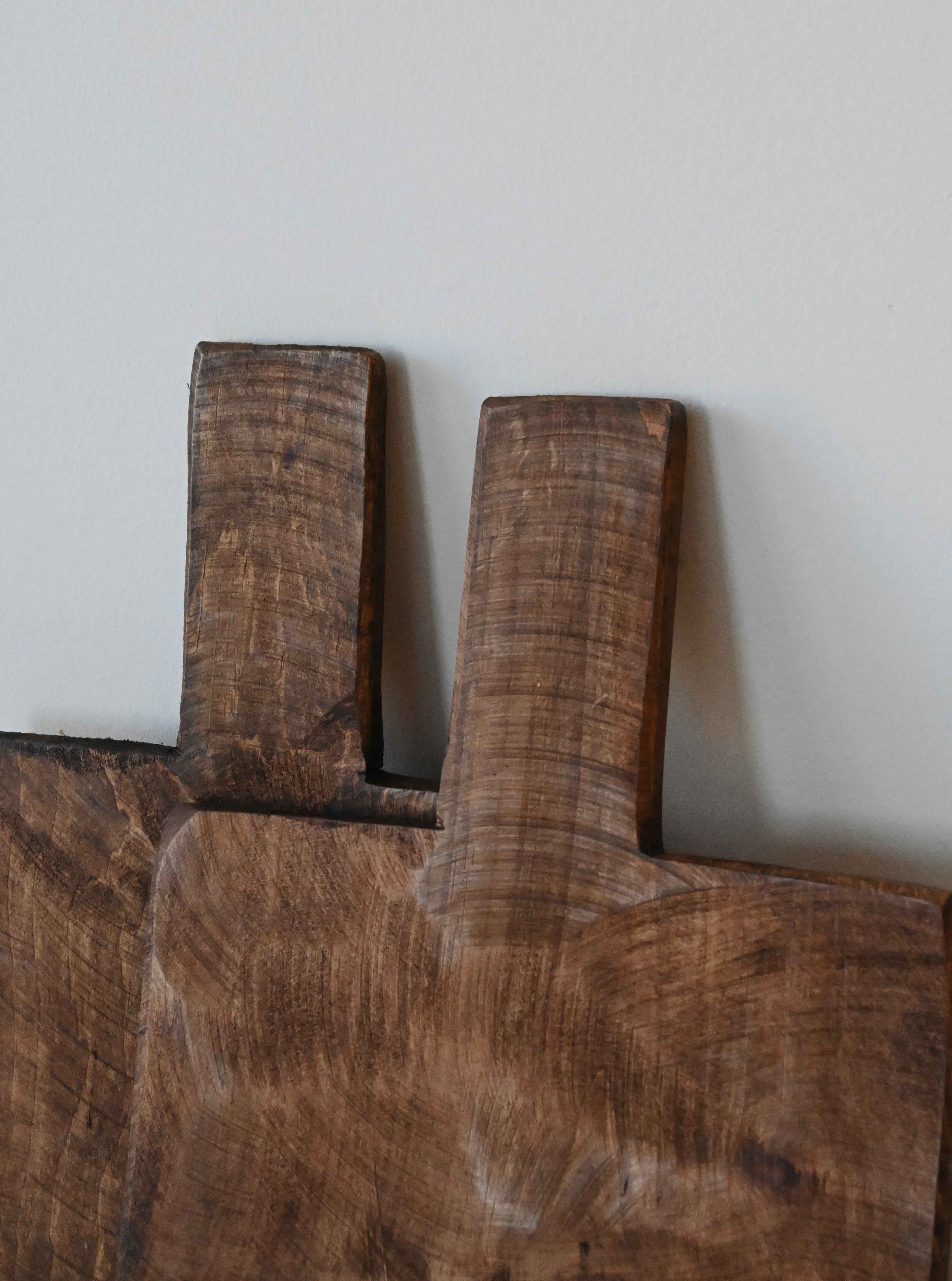 a close-up look of two dark mango wood boards used for kitchen decor or charcuterie boards sitting on a blank white wall