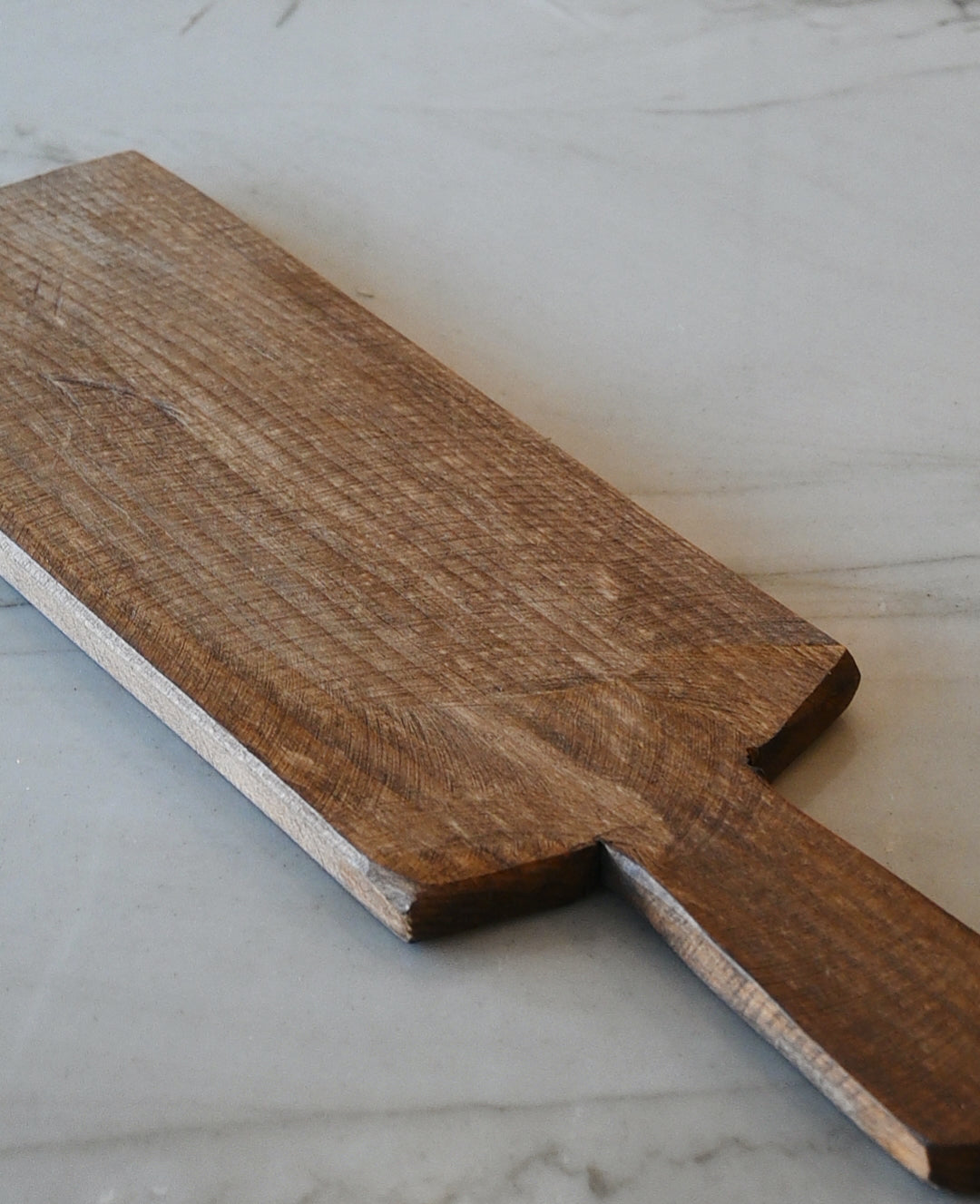 a long mango wood charcuterie board sitting on top of marble counter