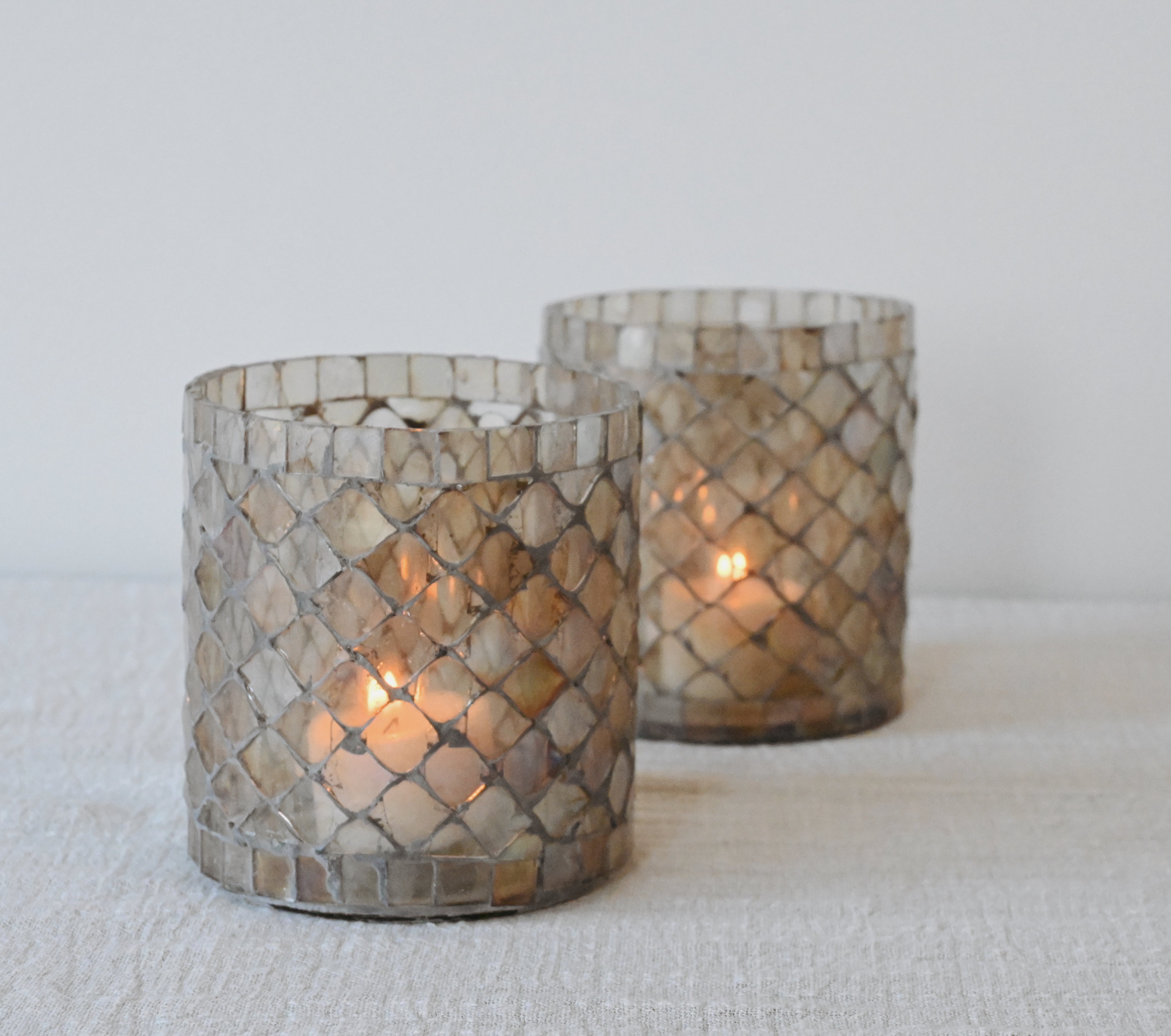 two glass votive candle holders sitting on a white table