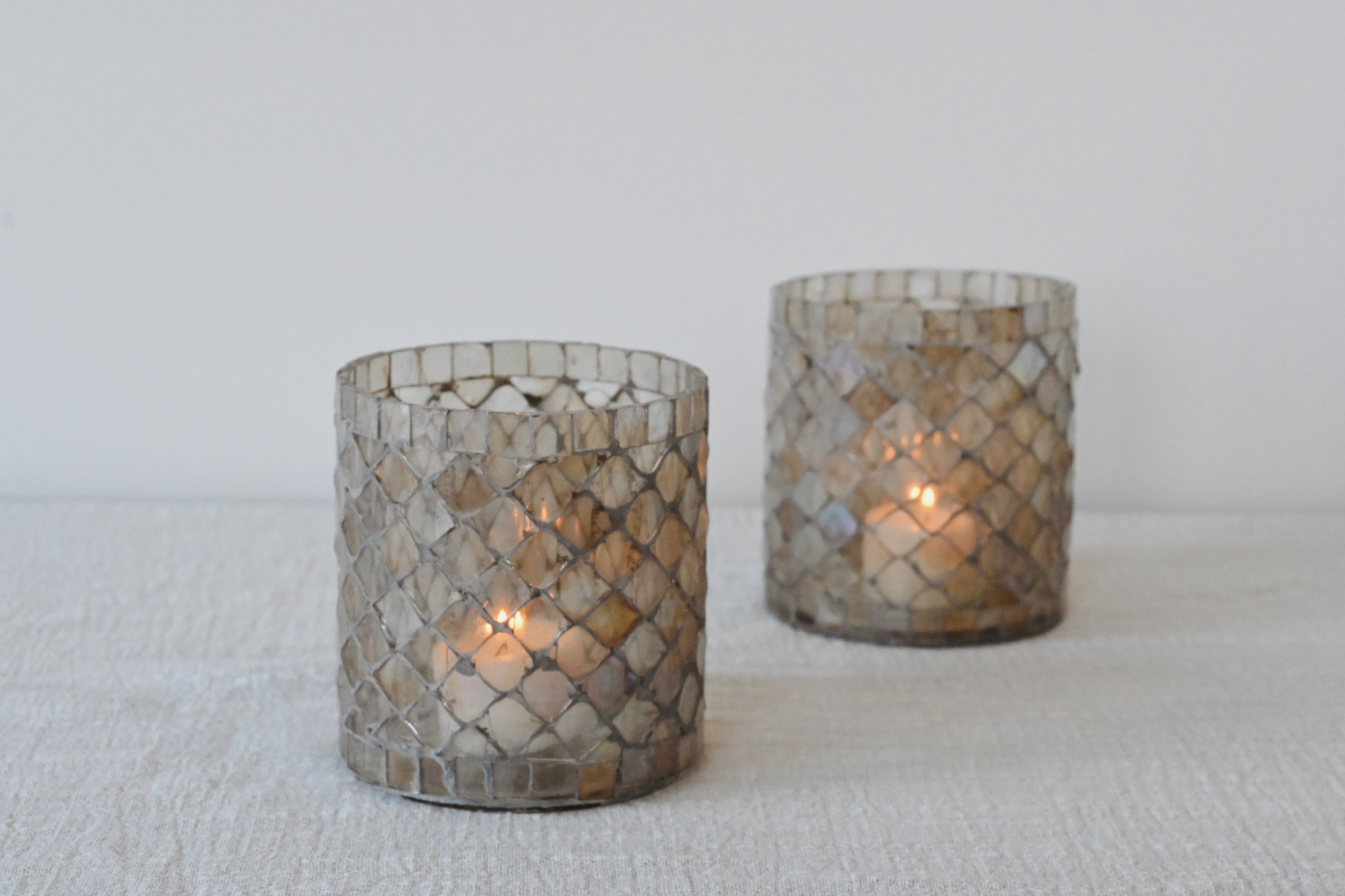 two glass votive candle holders sitting on a white table