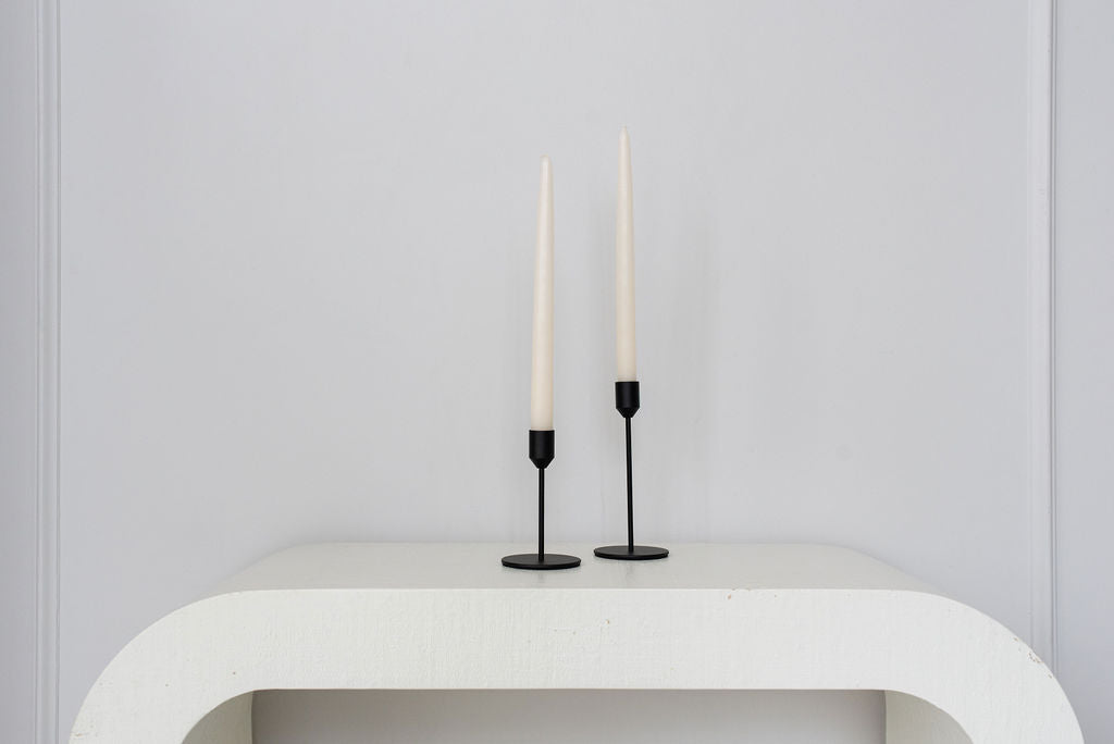 black candle holder centered on modern white side table white background
