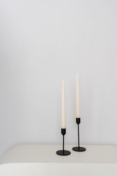 black candle holders different heights on white table with white background