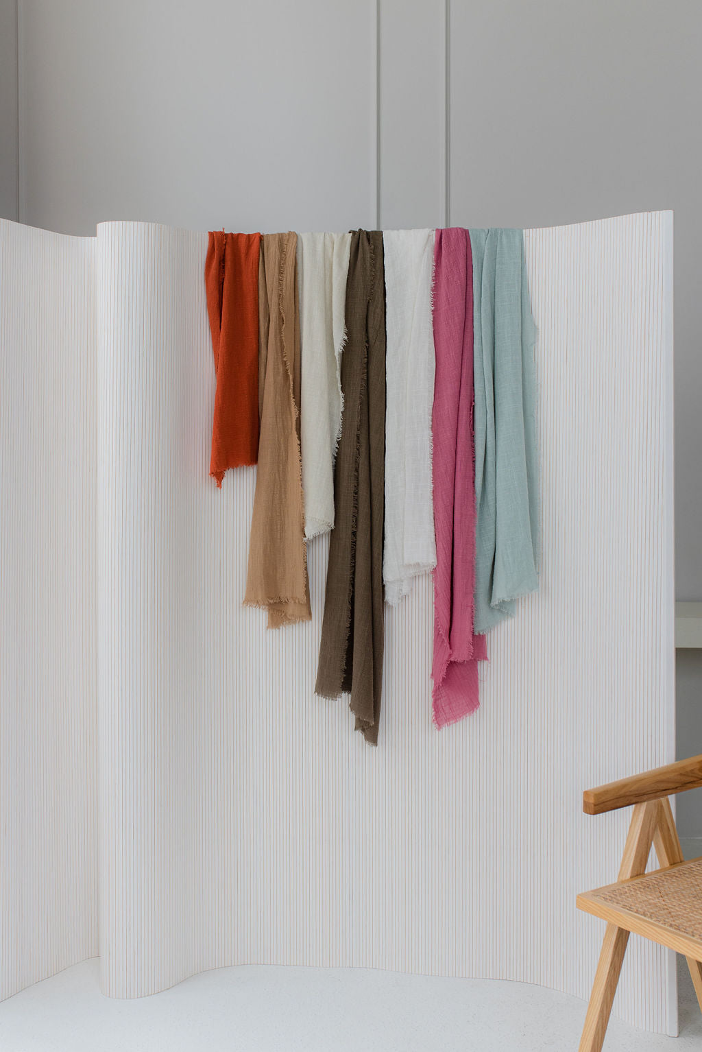multiple maison table runners in various colours draped over textured privacy screen