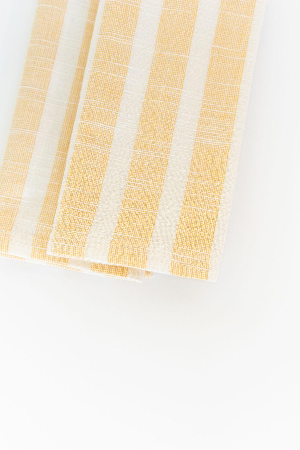 two folded yellow striped cotton napkins going off top of photo frame white background