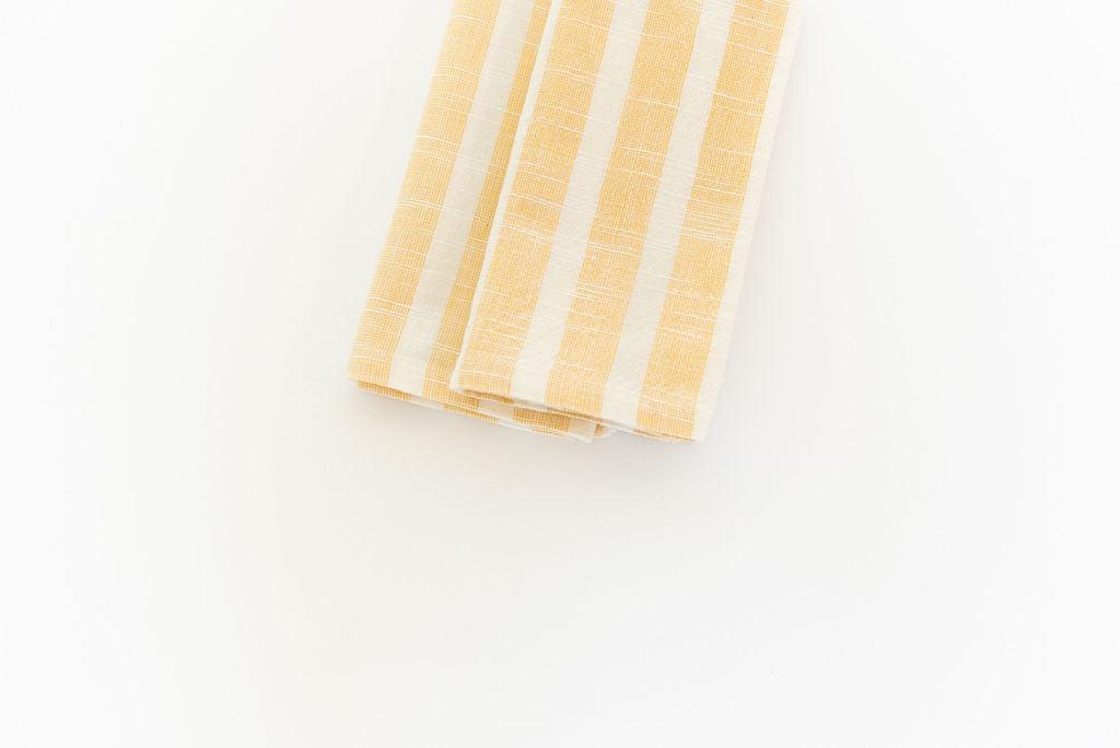 two centered folded yellow striped cotton napkins going off photoframe  white background