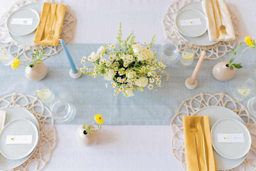 white table light blue maison table runner with centered floral arrangement and four solid yellow cotton napkin place settings