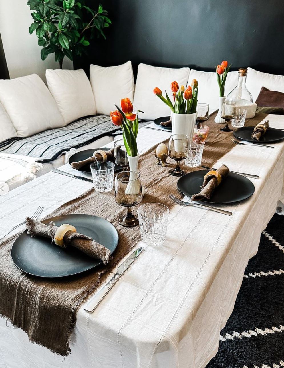 simple table setting with table cloth, napkins, table runner and black plates and cocktails and wine glasses