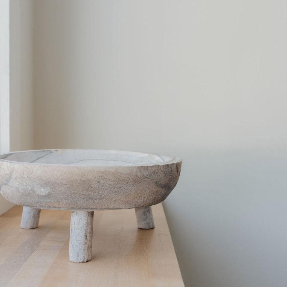 seaside footed wooden bowl on wooden surface natural light coming from window off frame