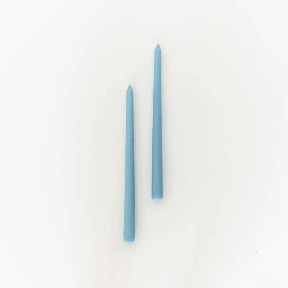 two blue tapered candles staggered centered on white background