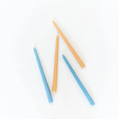 four tapered candles two light colour two a blue colour randomly flat layed on white background