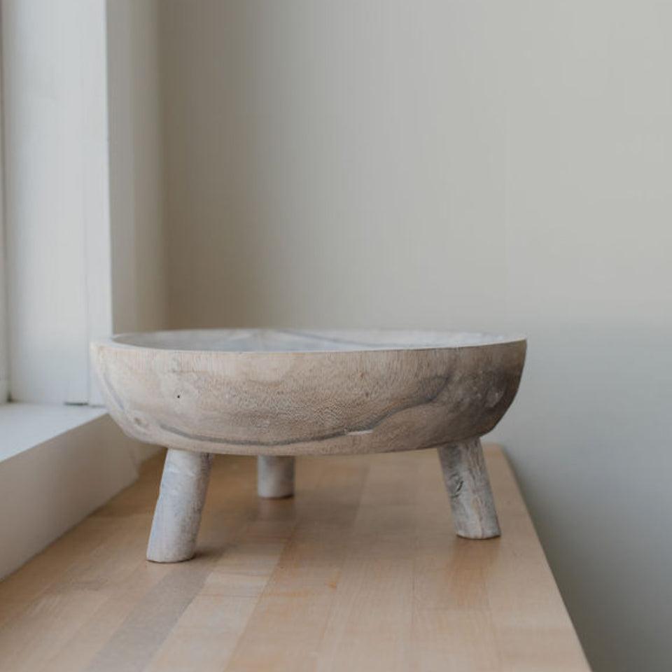 seaside footed wooden bowl on wooden surface natural light coming from window off frame closer up